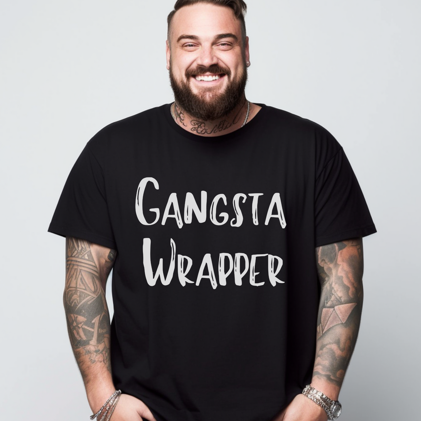 A person wearing a black unisex T-shirt with the text 'GANGSTA WRAPPER' printed on the front.