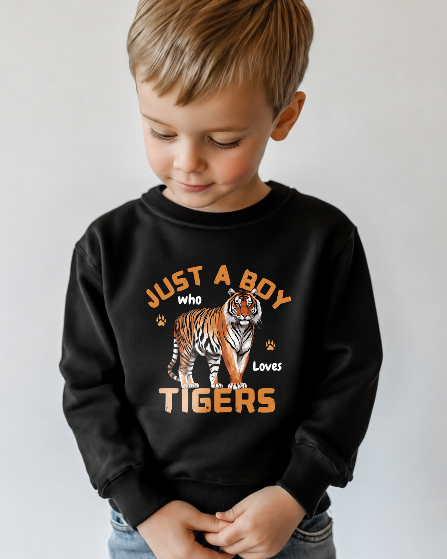 Little boy wearing a black sweatshirt featuring a bold tiger graphic and the phrase "Just a Boy Who Loves Tigers" design with foot prints and claw marks.