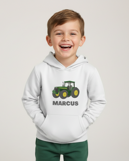 Smiling boy modelling white custom name tractor hoodie in studio, hands in pocket, front design visible.