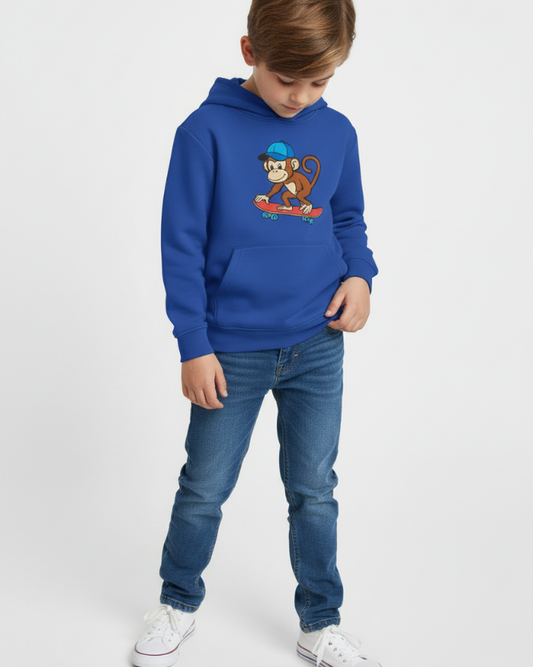 Full body view of boy wearing royal blue kids hoodie with skateboarding monkey graphic, studio background