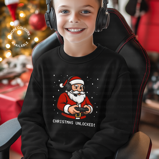 Smiling boy wearing black Christmas sweatshirt with a cartoon Santa holding a gaming controller and the slogan "Christmas Unlocked!" – perfect for kids who love video games