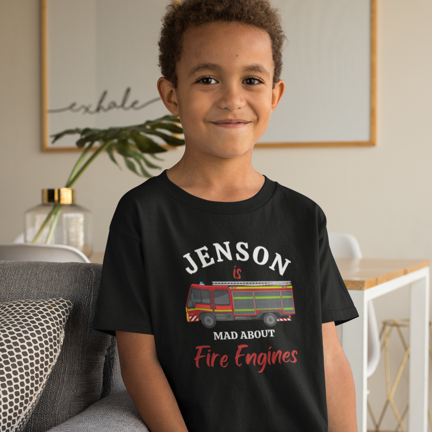 Young boy wears a black cotton t-shirt with British red fire engine illustration and "Jenson is mad about fire engines" printed on the front.