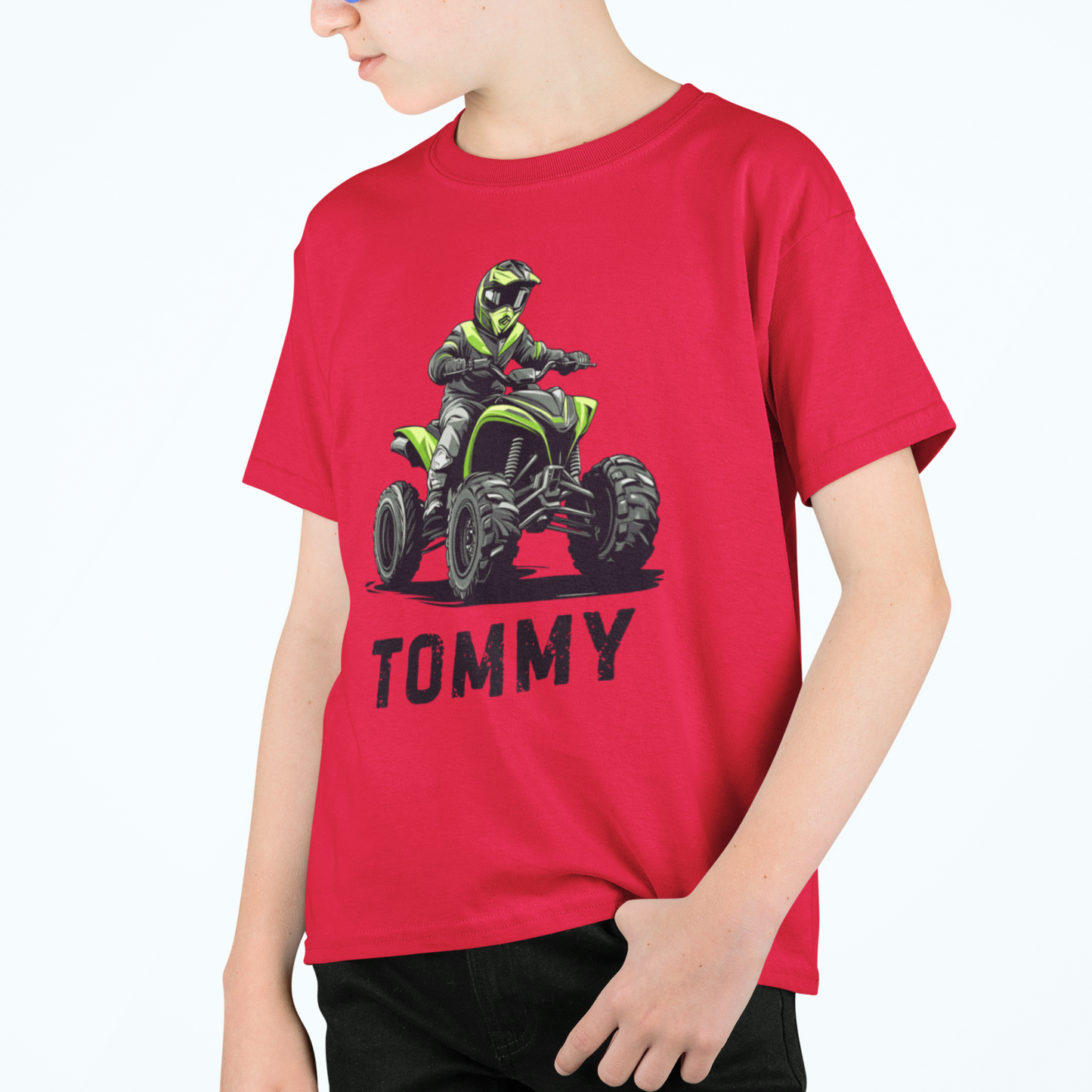 Child wearing a red t-shirt with a graphic of a person on a quad bike and the name 'Tommy'.