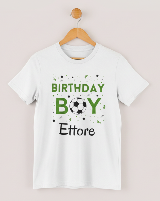 White personalised “Birthday Boy” football t-shirt with green text and soccer ball design, name Ettore printed on the front, displayed on a wooden hanger