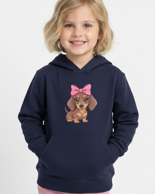 Girl wearing navy kids hoodie with cute dachshund puppy graphic and pink bow, studio product photo, front view