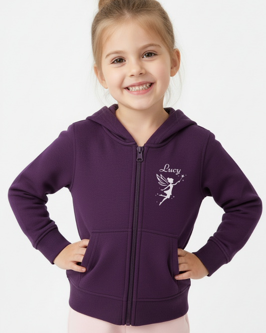 Young girl wearing a purple zip up hoodie with a fairy design and 'Lucy' text on a white background