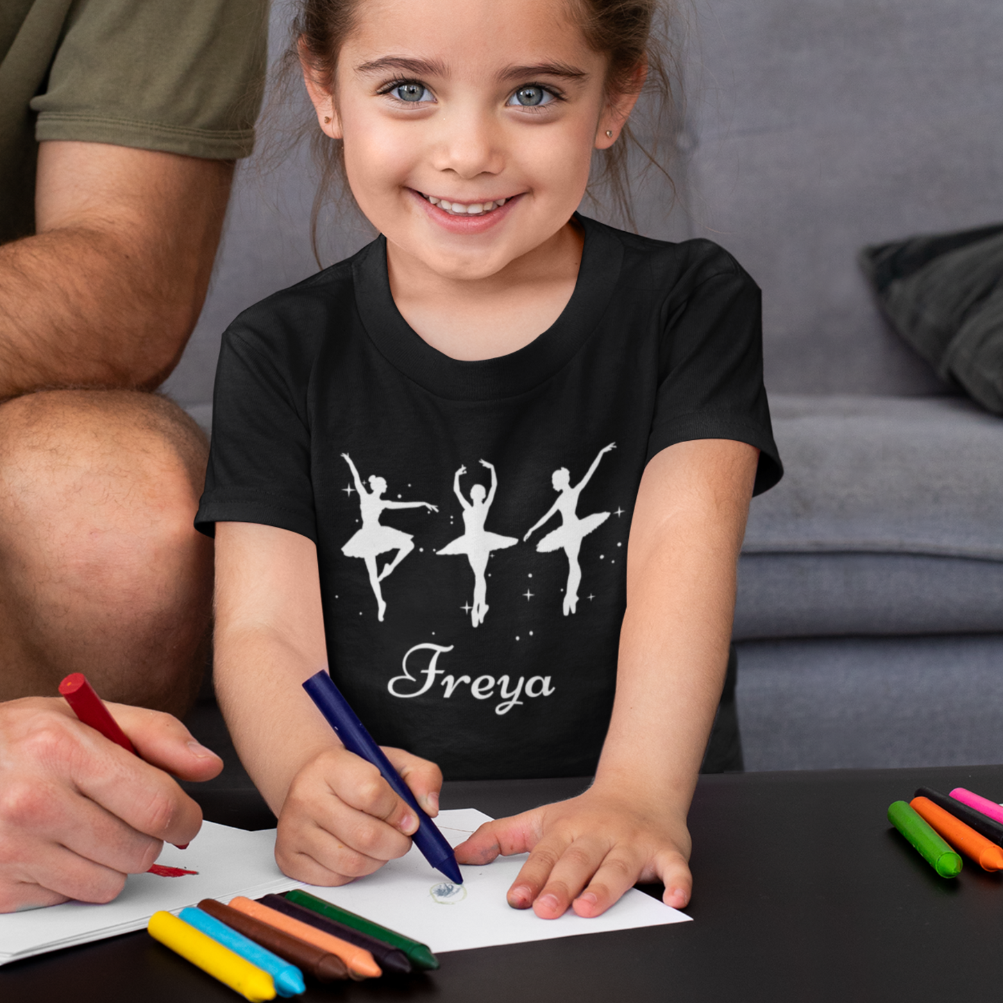 Young girl modelling a black personalised ballet t-shirt with three white ballerina silhouettes a custom name printed beneath the design