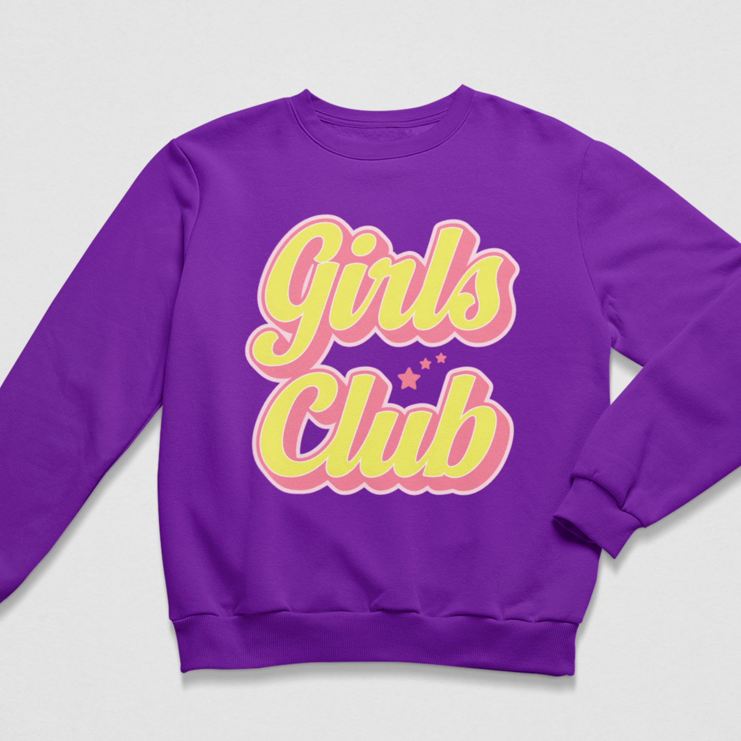 A girls purple crewneck sweatshirt featuring a retro-style graphic on the chest that reads 'Girls Club' in yellow bubble letters with a pink outline, accented by small pink stars, shown on a light grey background.
