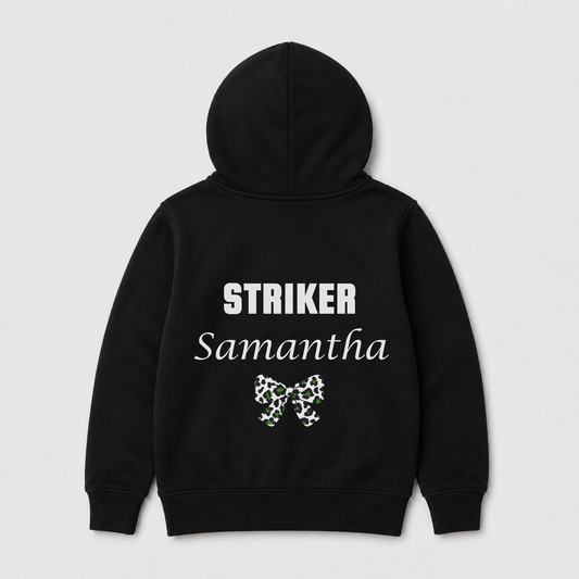 Kids football-themed black zip hoodie shown from the back, featuring the word 'STRIKER' in white block letters, 'Samantha' in white script, and a small green and white bow graphic below. The hoodie is displayed on a light grey background.