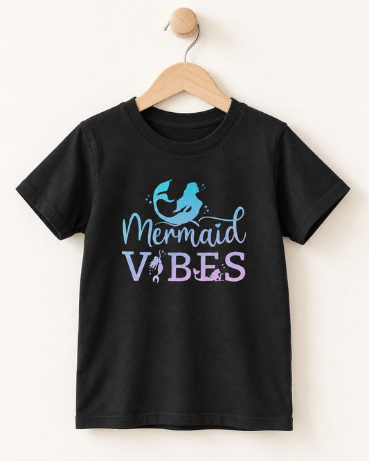 Black short sleeve girls’ Mermaid Vibes T-shirt with blue and lilac ombre mermaid design displayed on a wooden hanger