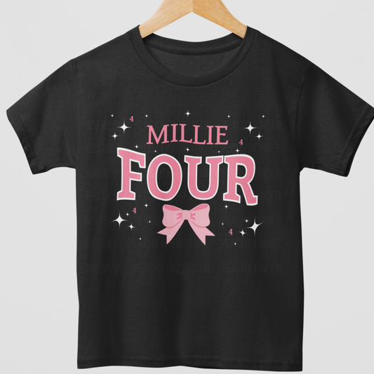 A girls short sleeved t-shirt in black featuring a bold pink and white number “Four” with pink bow, stars and custom name - styled on a wooden hanger.