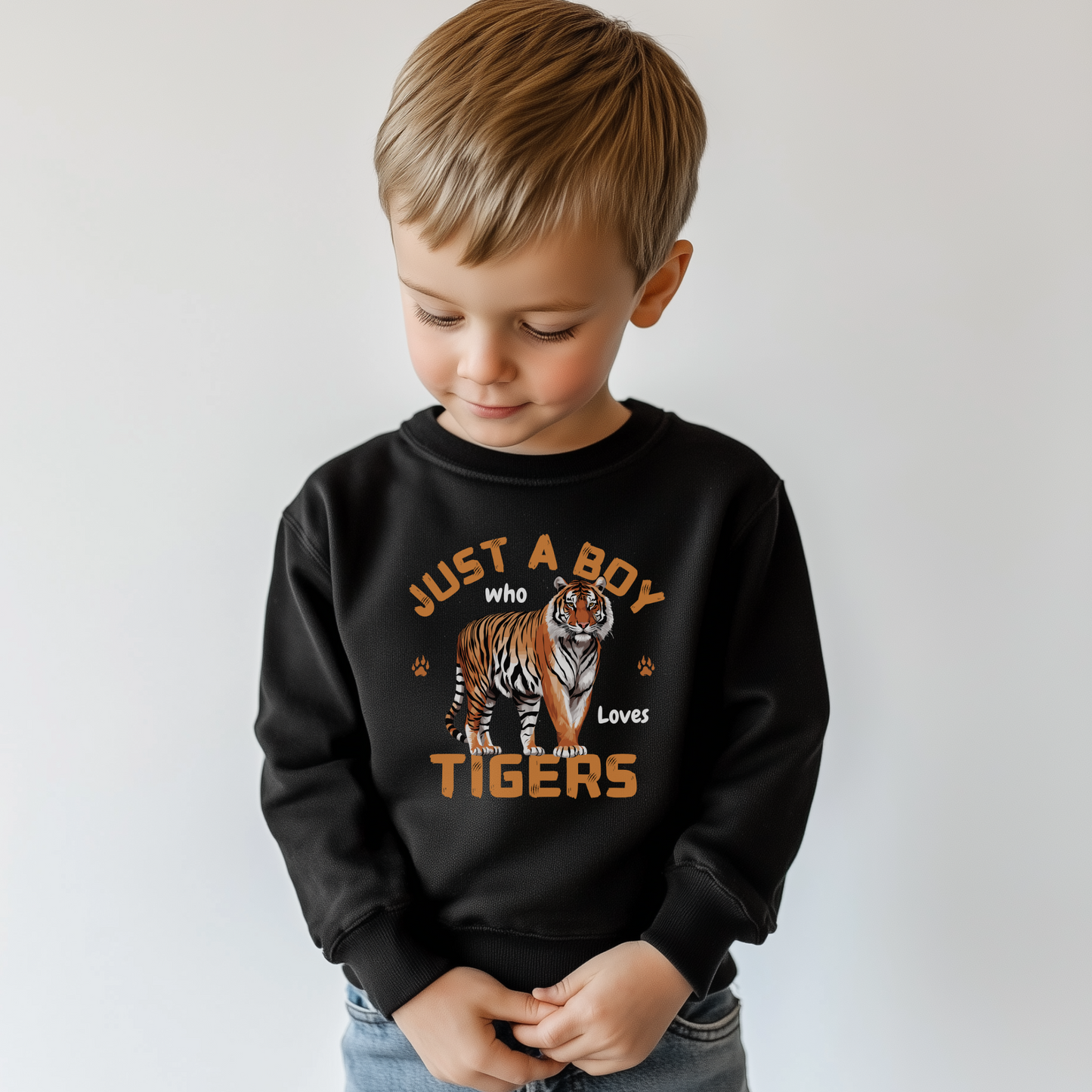 Little boy wearing a black sweatshirt featuring a bold tiger graphic and the phrase "Just a Boy Who Loves Tigers" design with foot prints and claw marks.