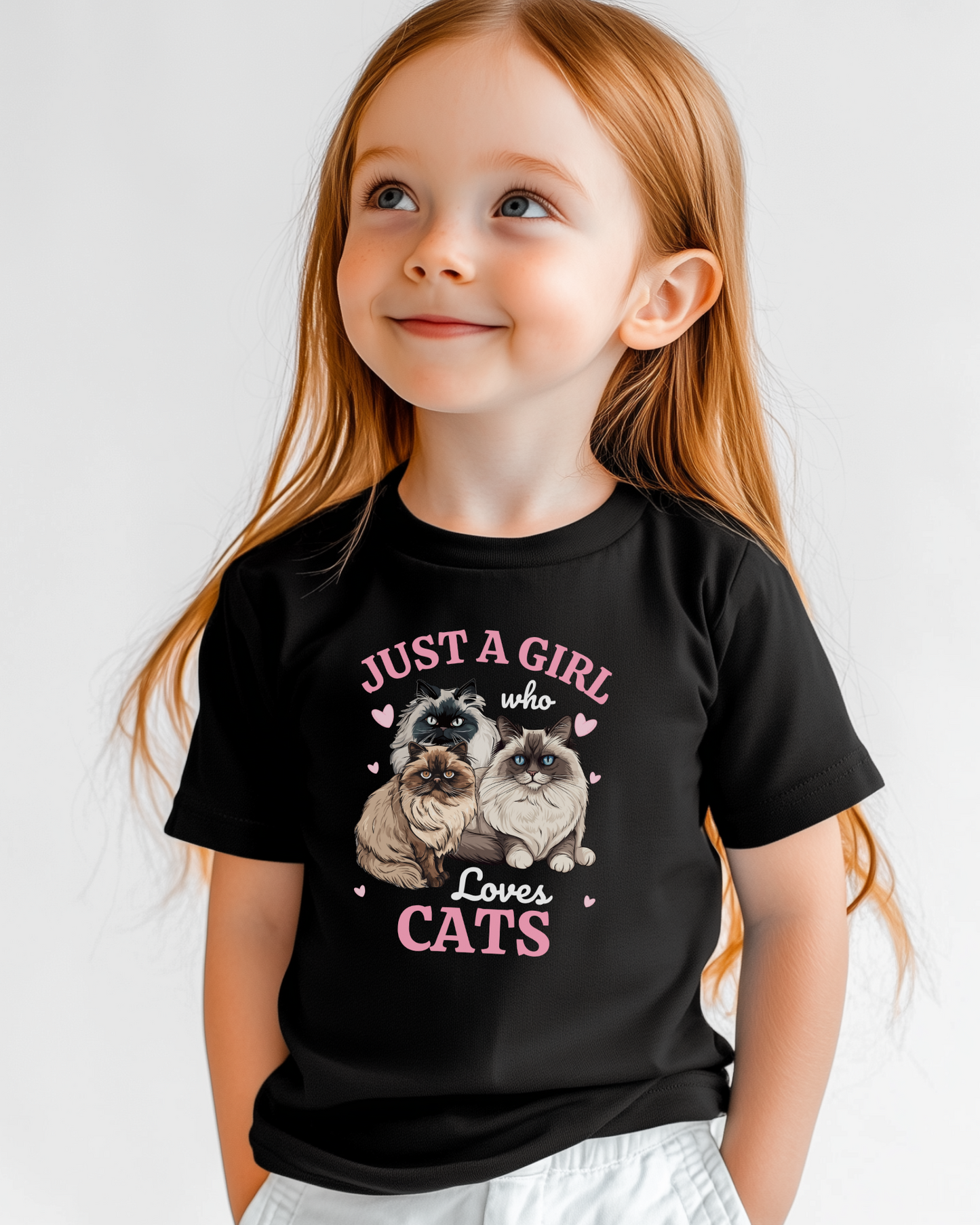 Little girl modelling a black t-shirt featuring three fluffy Ragdoll and Persian cats surrounded by pink hearts and the text ‘Just a Girl Who Loves Cats’