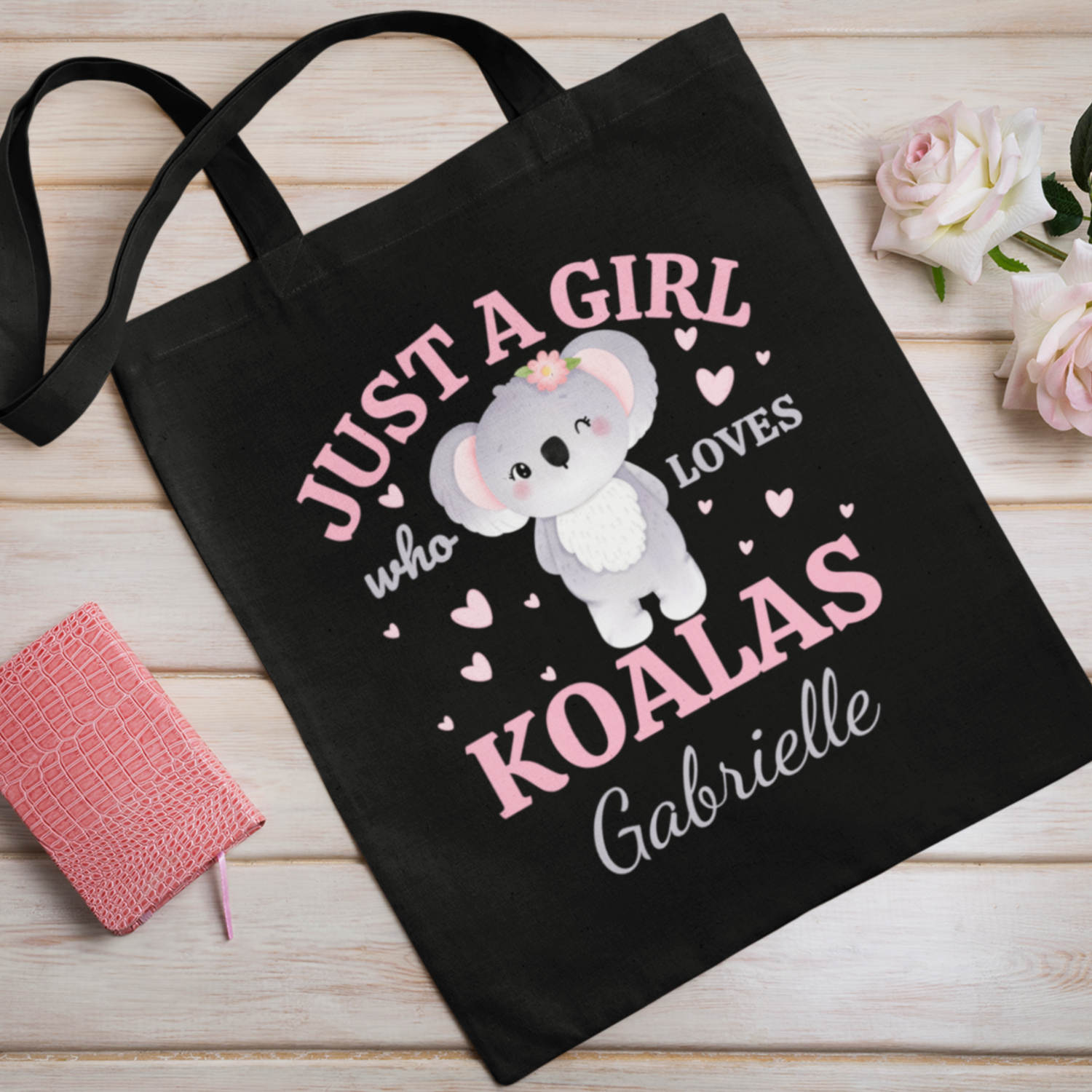 Black cotton tote bag featuring a cute cartoon koala surrounded by pink hearts and the text “Just a Girl Who Loves Koalas,” with the personalised name “Gabrielle” printed underneath.