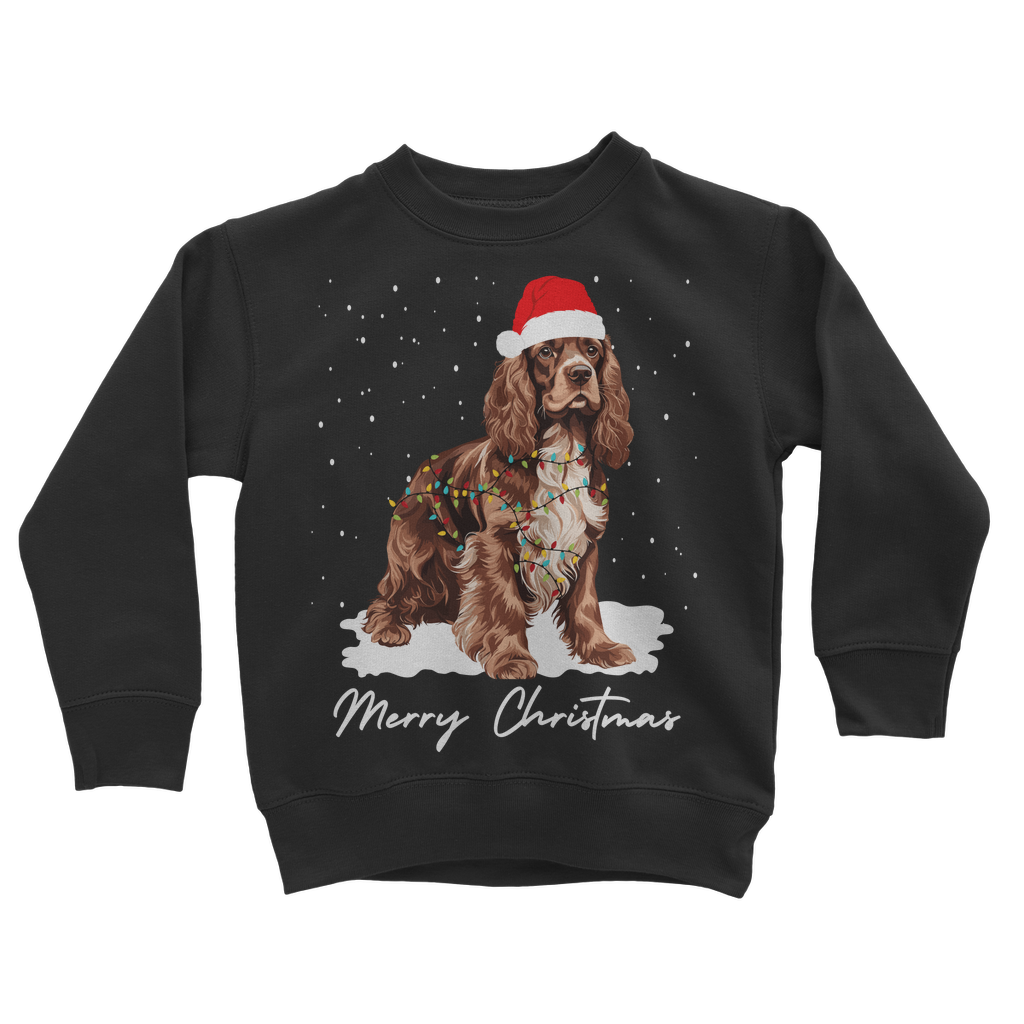 Kids black Christmas sweatshirt featuring a brown and white Cocker Spaniel, wearing Santa hat, wrapped in Xmas lights with falling snow design.