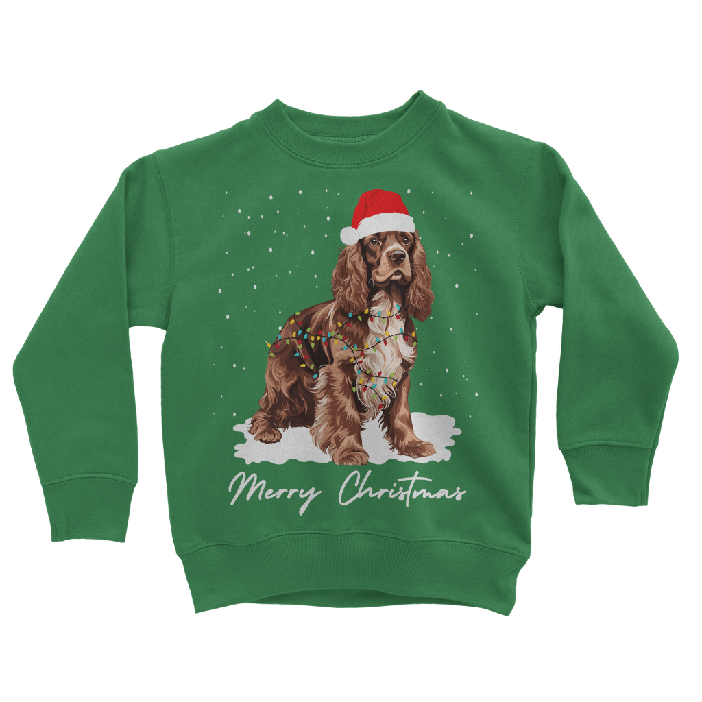Kids green Christmas sweatshirt featuring a brown and white Cocker Spaniel, wearing Santa hat, wrapped in Xmas lights with falling snow design.