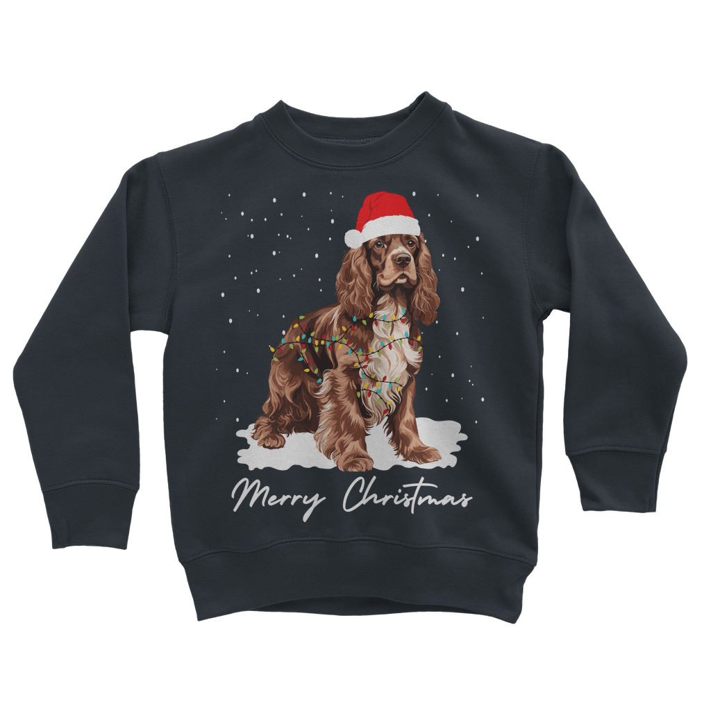 Kids navy Christmas sweatshirt featuring a brown and white Cocker Spaniel, wearing Santa hat, wrapped in Xmas lights with falling snow design.