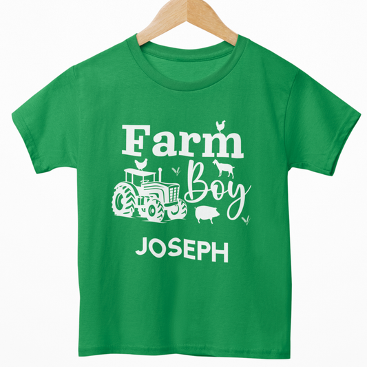 Kids green “Farm Boy” T-shirt with white tractor and farm animals design, personalised with the name in white text underneath. Styled on a wooden hanger.