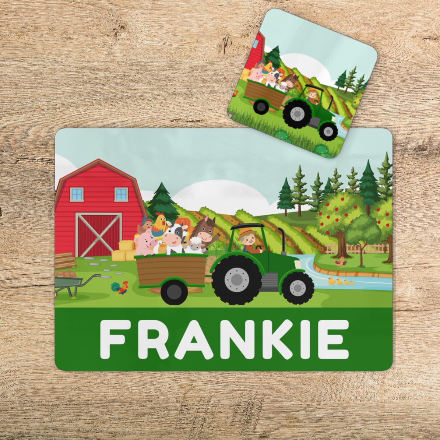 Personalised kids farm placemat and coaster set with green tractor, barn and farm animals, name “Frankie” printed along the bottom, styled on a wooden table.