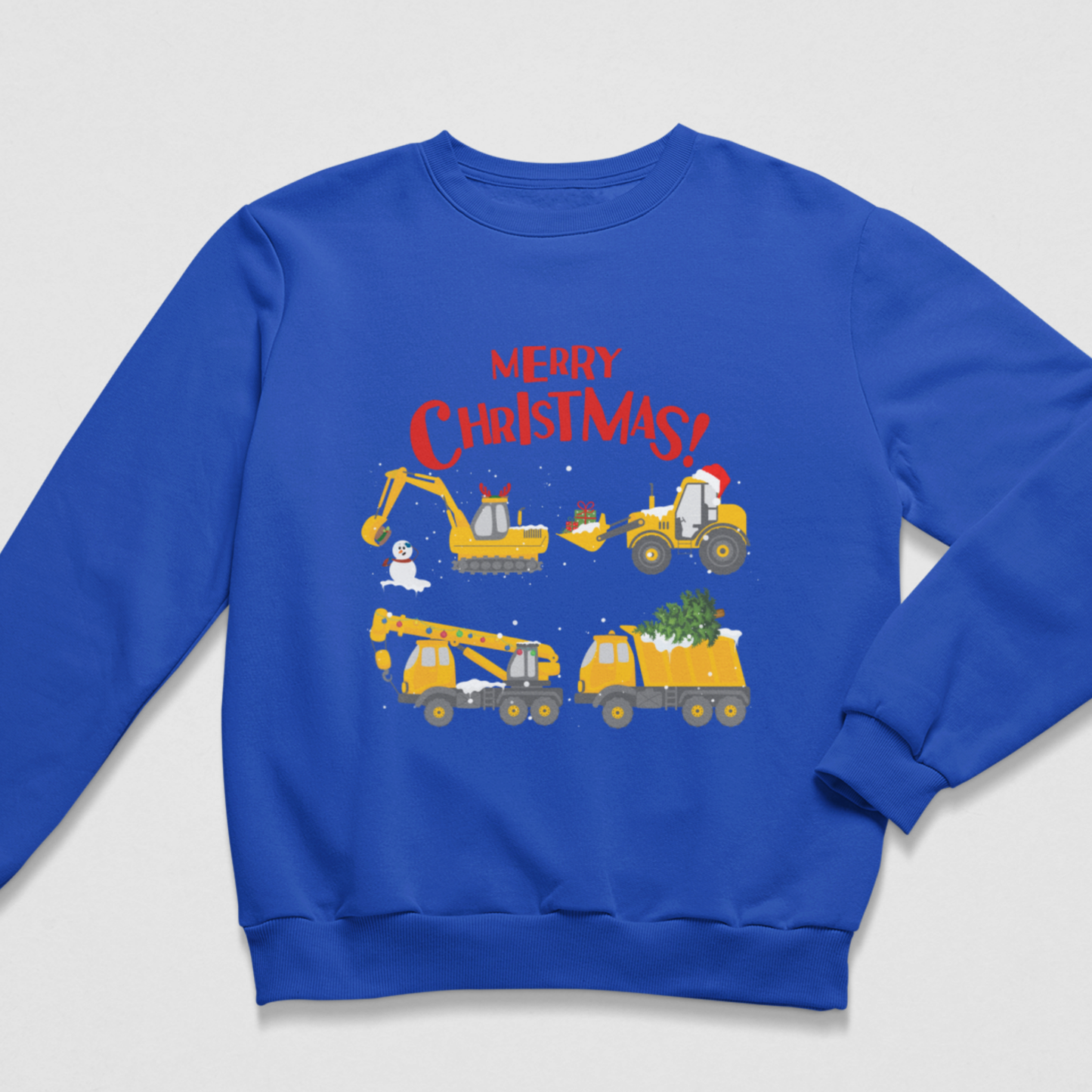 A kids royal blue crewneck sweatshirt featuring a festive graphic print of construction vehicles with Christmas-themed humour, including a snowman, Santa, and a Christmas tree, with the text 'MERRY CHRISTMAS!' in red.