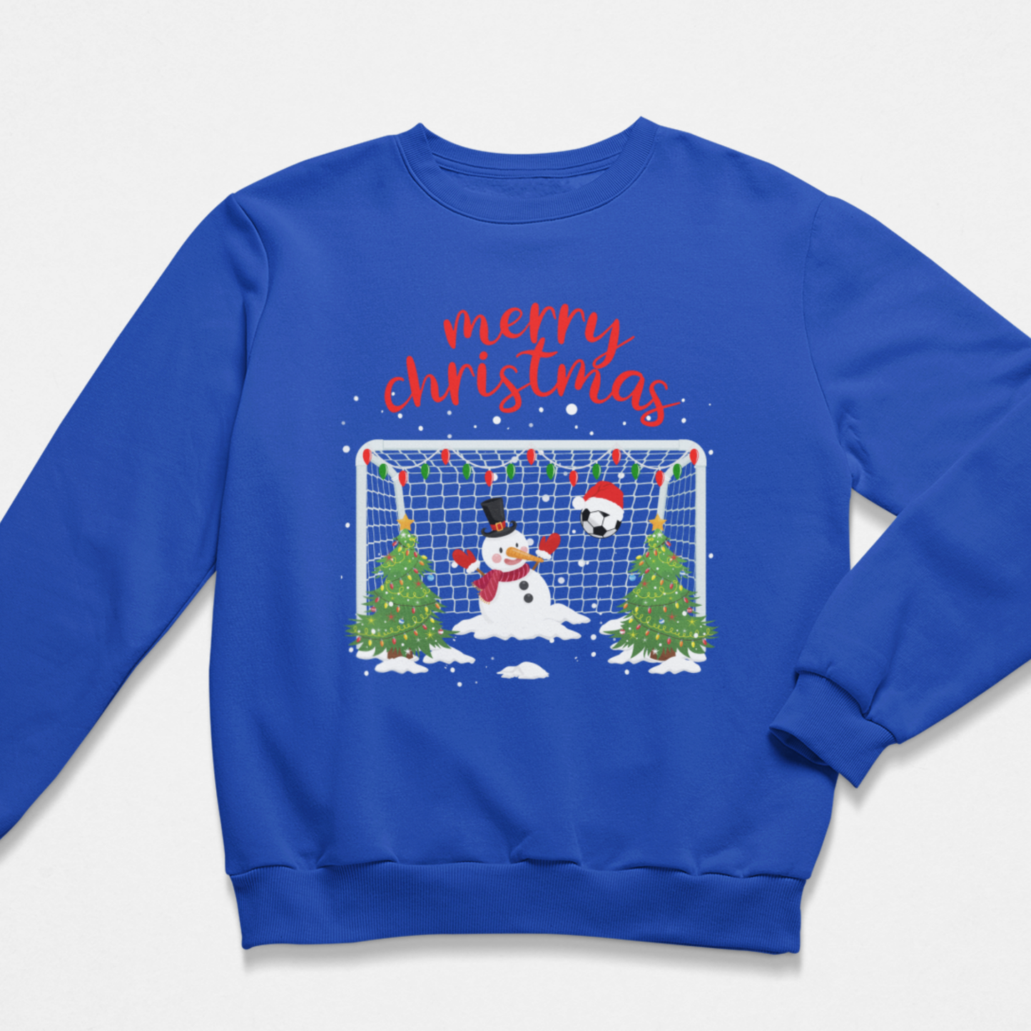 A boys royal blue crewneck sweatshirt featuring a festive Christmas soccer graphic on the front. The design includes the text 'merry christmas' in red script above a scene with a snowman, a soccer ball, a goal net, and two decorated Christmas trees.