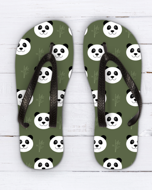 A pair of kids olive green flip-flops with a repeating panda face pattern and black straps, displayed flat on a white wood background.