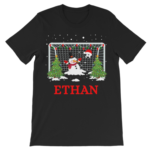 Children’s personalised Christmas football T-shirt in black featuring a snowman goalie, football goal, festive trees and custom red name.