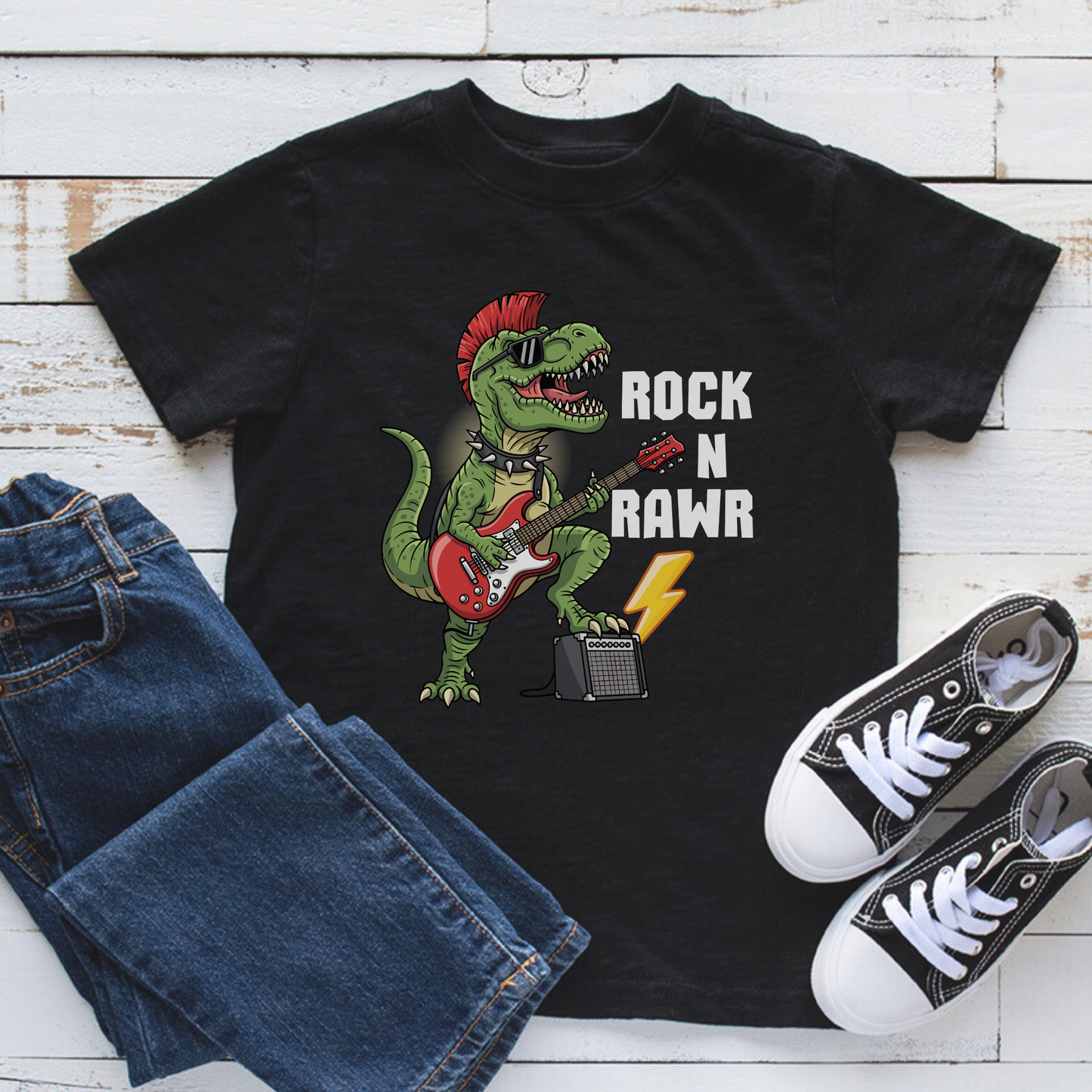 Boys ‘Rock N Rawr’ dinosaur guitar black short sleeved t-shirt – T-Rex playing red electric guitar with lightning bolt - styled with jeans and shoes.