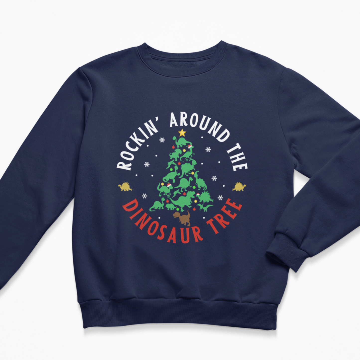 A kids navy blue crewneck sweatshirt featuring a festive Christmas tree graphic on the chest with the text 'ROCKIN' AROUND THE DINOSAUR TREE' in white and red, decorated with a green tree, yellow stars, and white snowflakes.