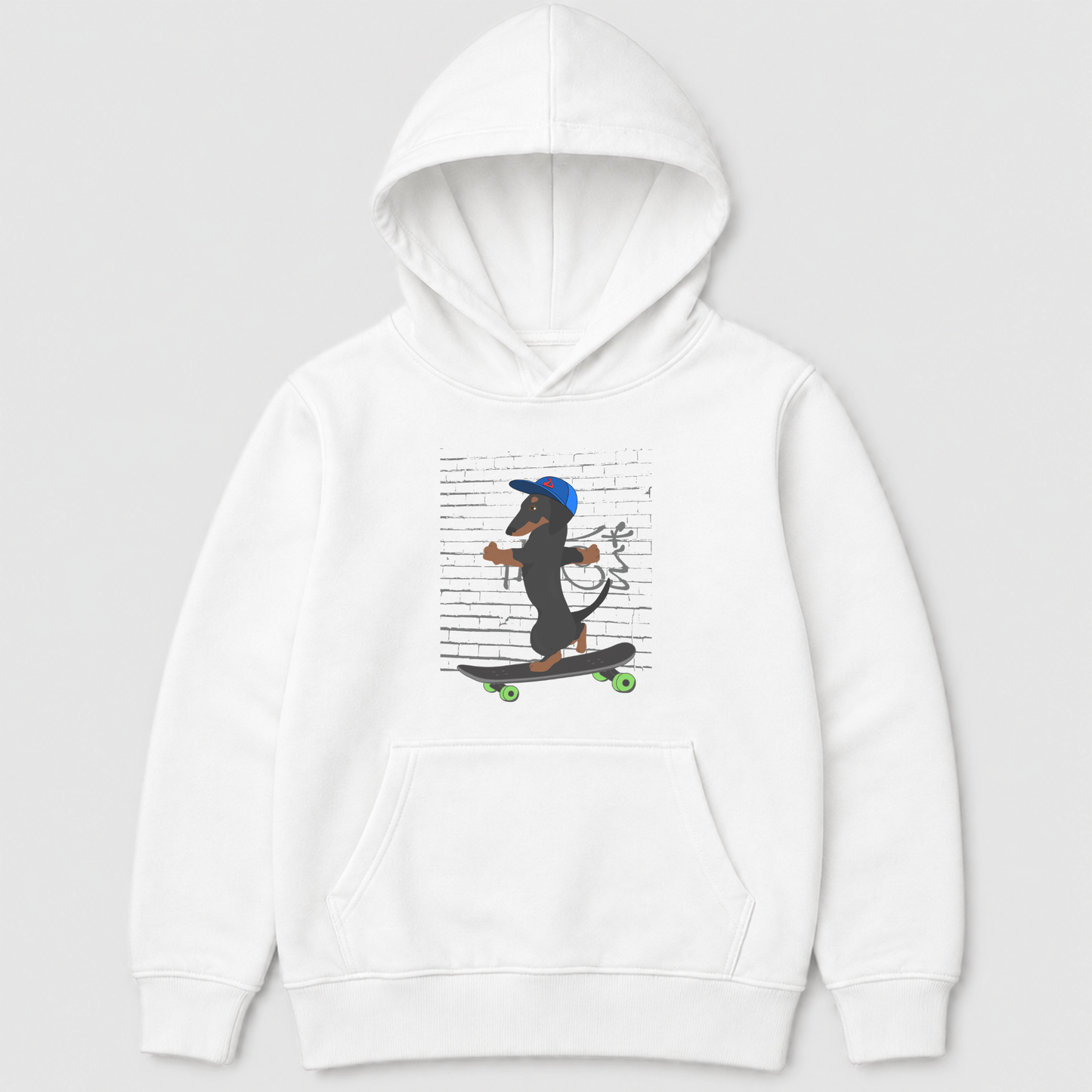 A kids white pullover hoodie featuring a cartoon graphic of a dachshund wearing a blue cap and riding a skateboard against a background of printed text, shown on a light grey studio background.