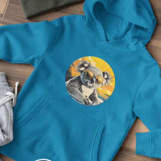 A bright blue kids hoodie features a cool koala, sporting sunglasses against a vibrant sunset. The laid back design evokes a relaxed, summery feel.