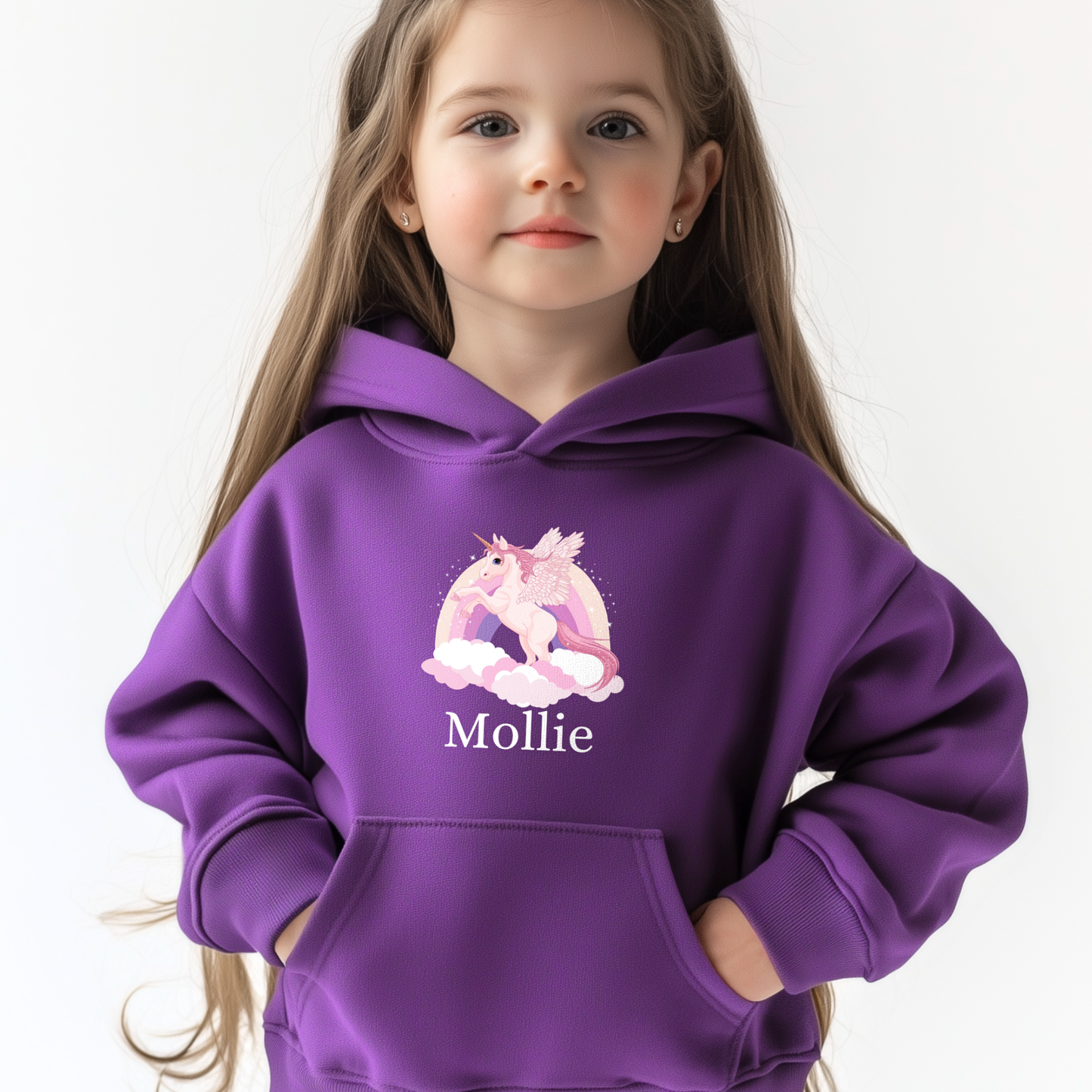 Young girl wearing a purple hoodie with a pastel unicorn, rainbow, and clouds print above the custom name.