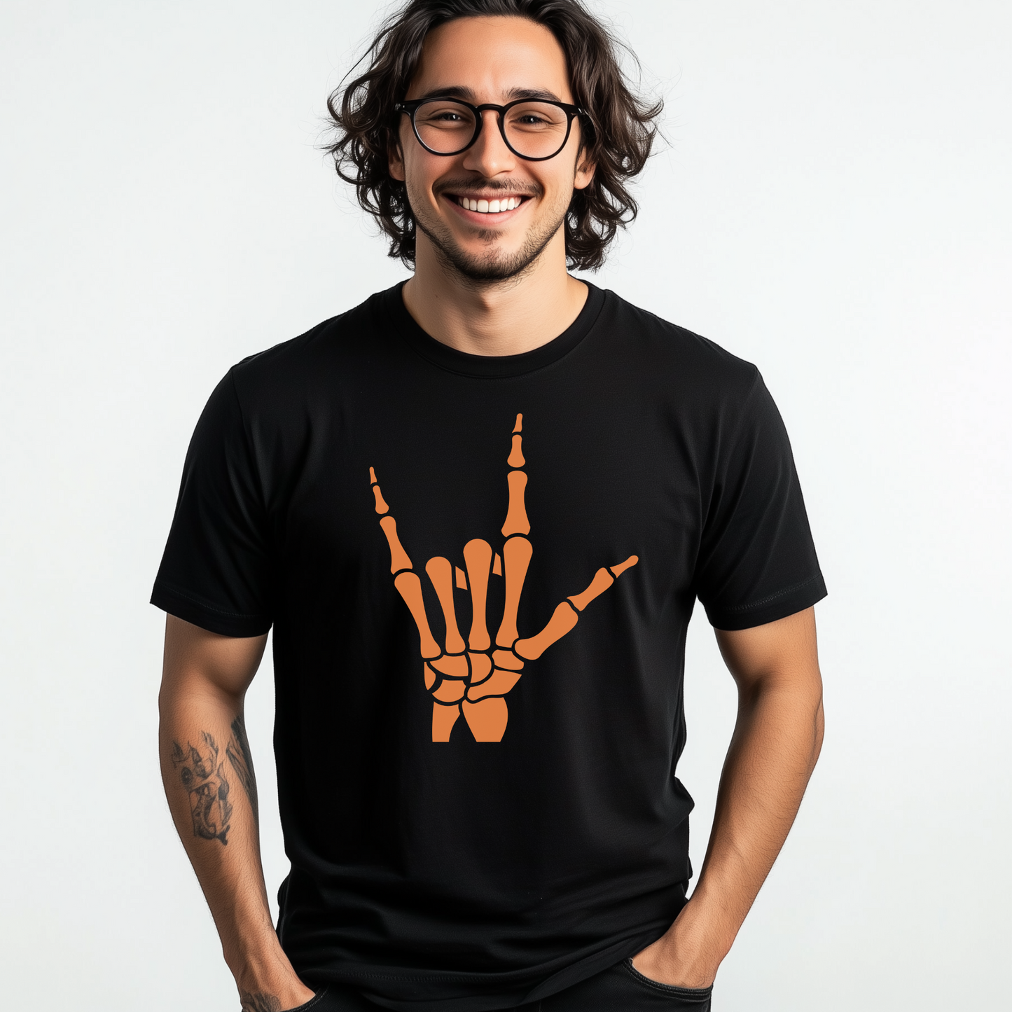 A young man wears a black t-shirt with a large orange rock-and-roll skeleton hand signal design in the centre, combining Halloween and music aesthetics.
