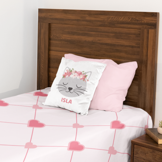 Personalised girls cushion cover featuring a cute grey cat with a pink floral crown and the custom name printed below, styled on a single bed