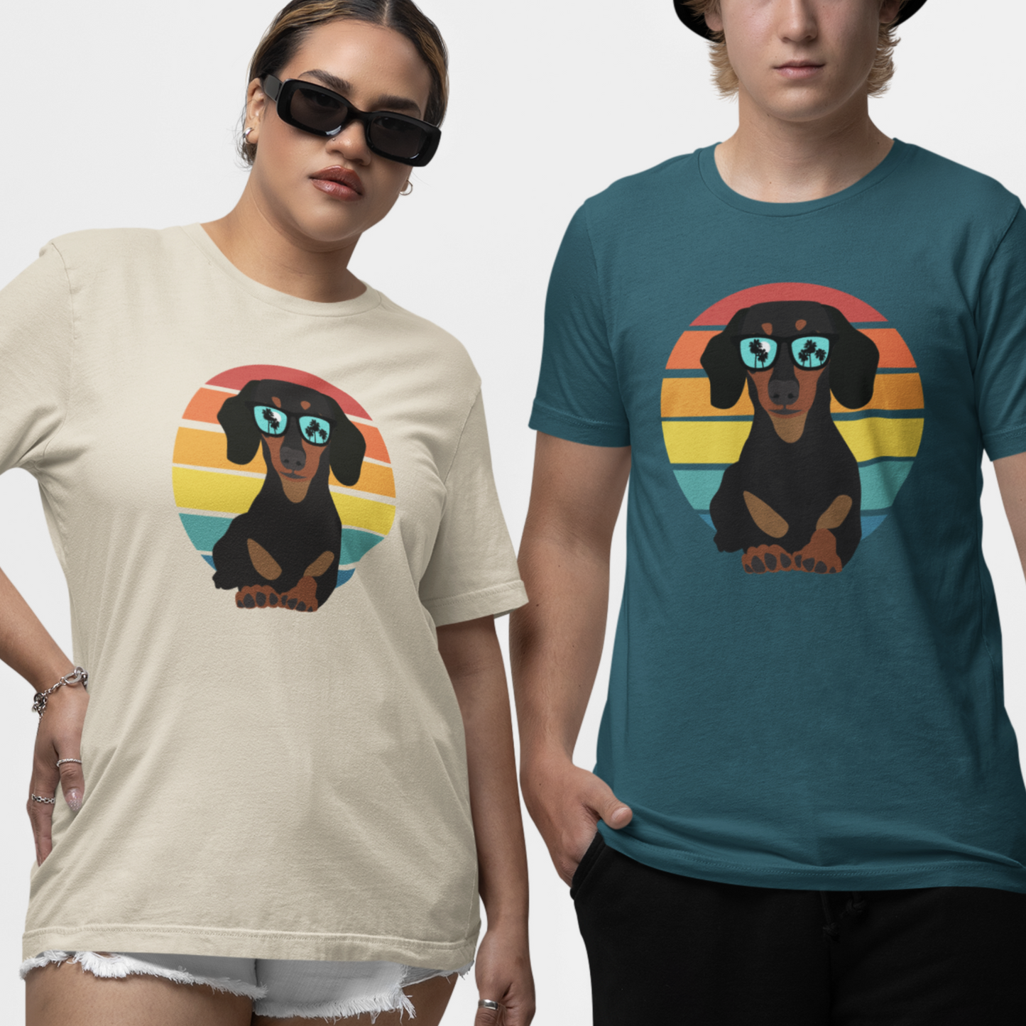 Man and woman stand side-by-side wearing t-shirts with a graphic of a dachshund wearing sunglasses against a retro striped circle. The left shirt is beige, and the right is teal.