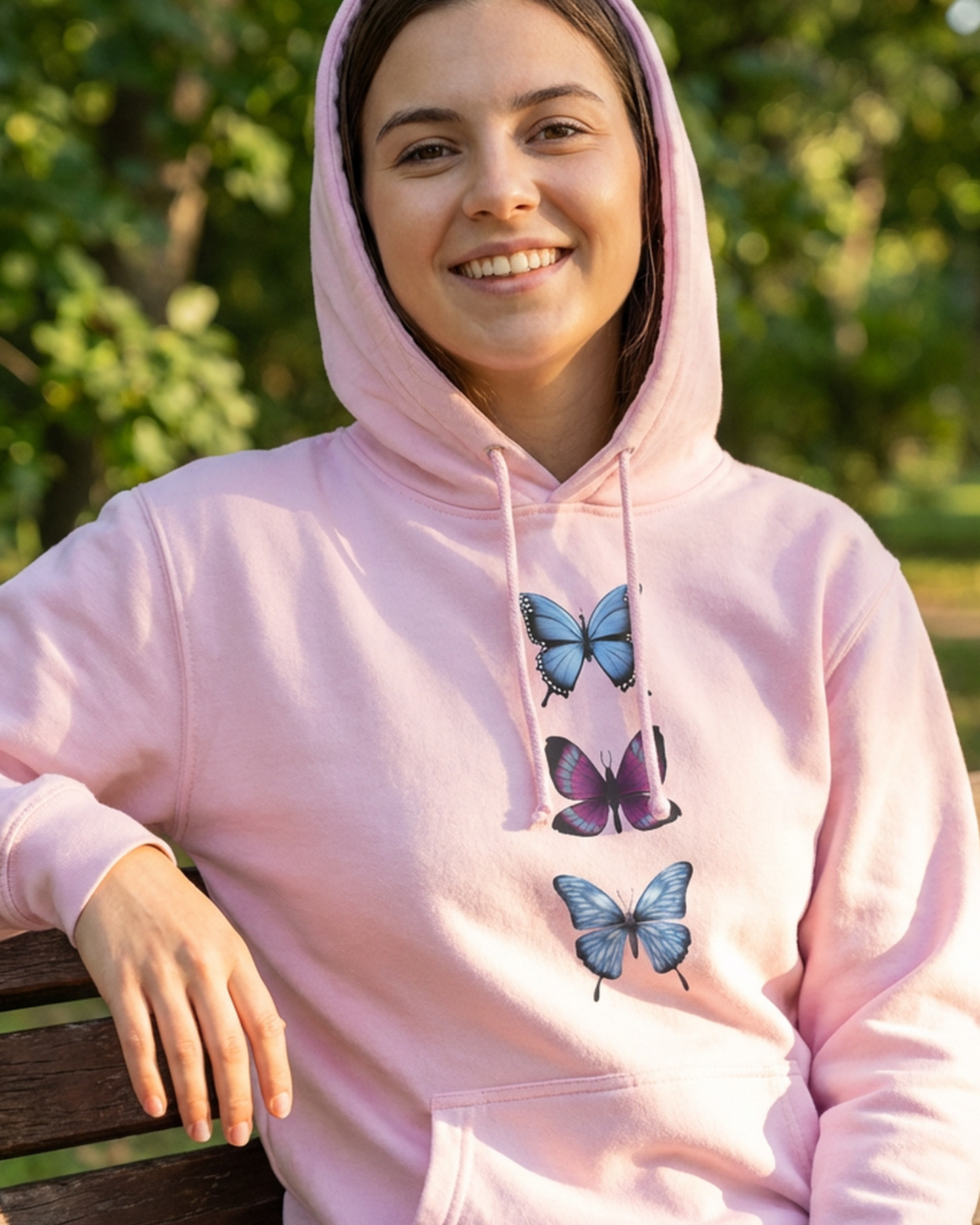Baby pink butterfly trio hoodie worn by a woman outdoors
