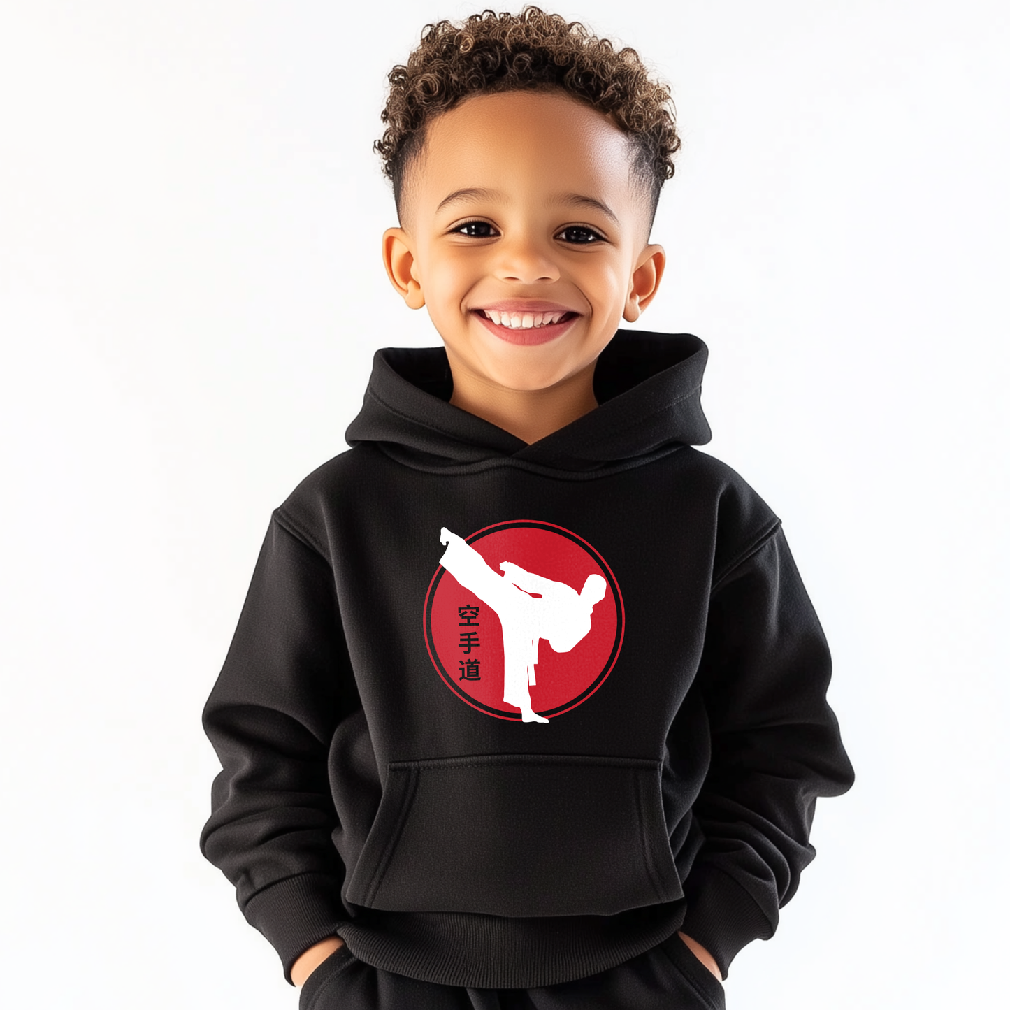Young boy wearing a kids karate hoodie featuring a white kicking silhouette inside a red circle with Japanese kanji symbols, smiling against a plain white background.