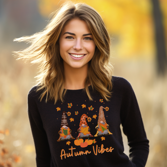 A woman wearing a black sweatshirt with printed autumn gonks design and words "Autumn Vibes"
