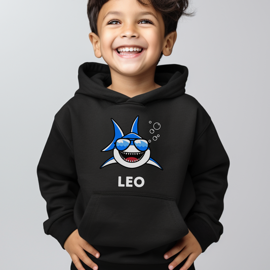 A little boy wearing a black hoodie with a printed cool shark design and personalised name in white  