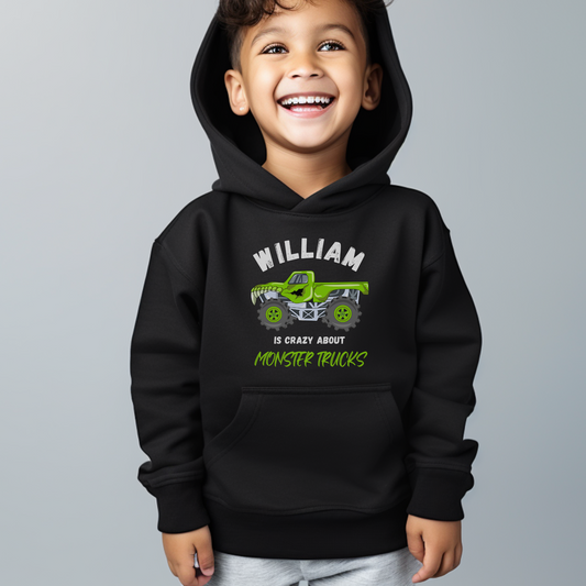 A little boy wearing black hoodie with a printed monster truck design and the words "William is crazy about monster truck"  