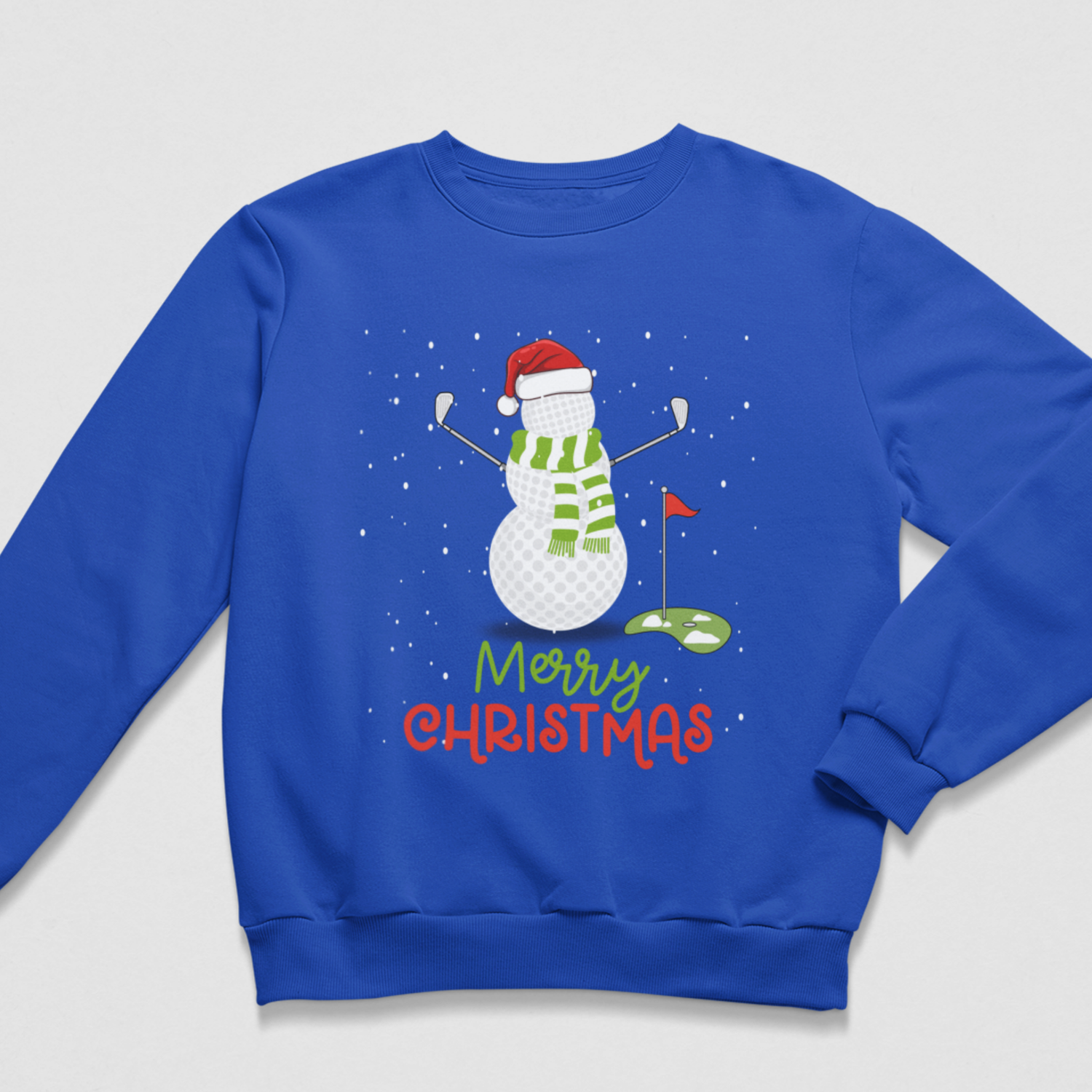 A royal blue crewneck sweatshirt featuring a Christmas-themed golf graphic. The design shows a snowman wearing a red Santa hat and green striped scarf, holding golf clubs near a green hole with a red flag, above the text 'Merry Christmas' in green and red.