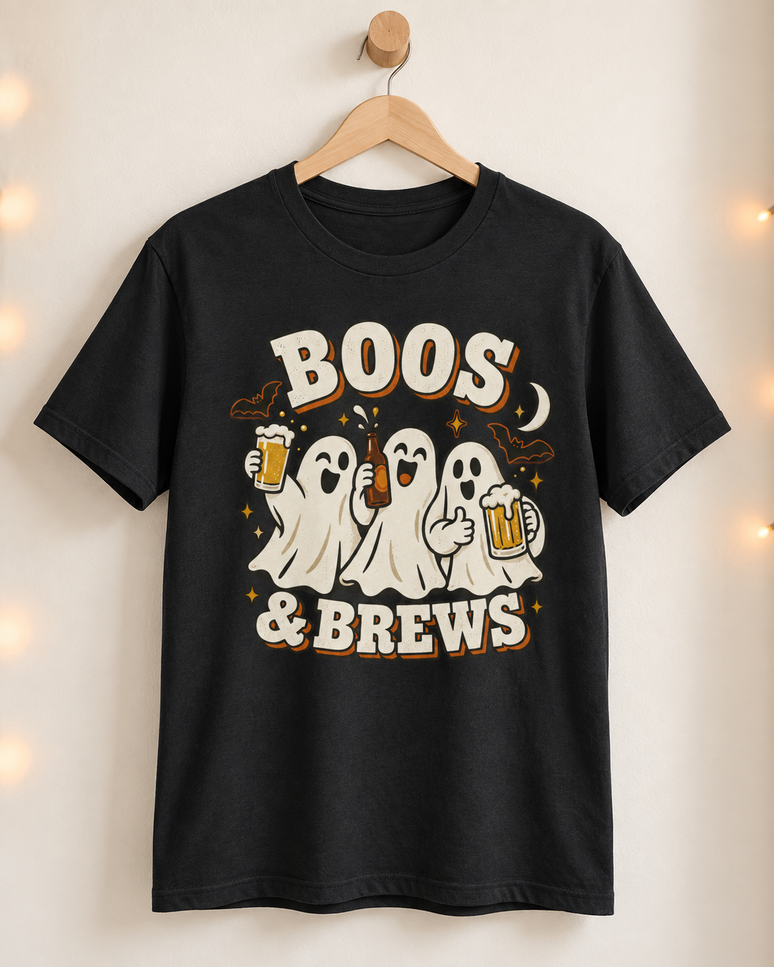 Black Boos and Brews ghost Halloween T-shirt displayed on a natural wooden hanger