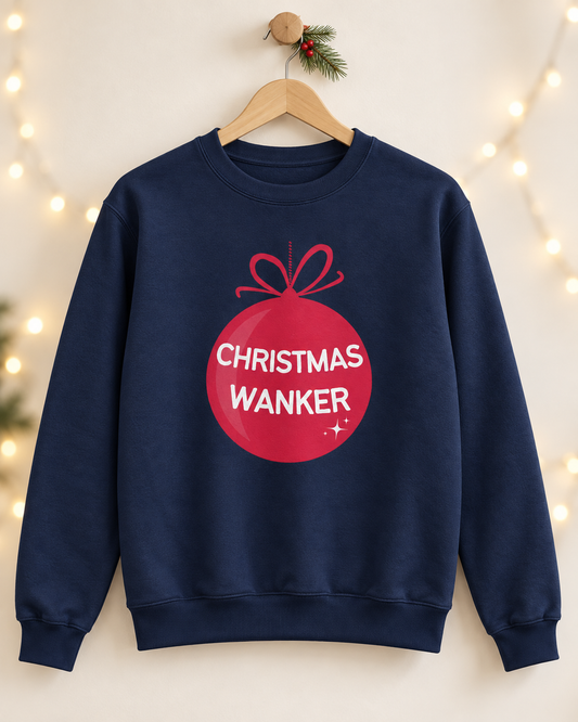 Navy Christmas Wanker sweatshirt displayed on a wooden hanger with festive greenery and warm fairy lights.