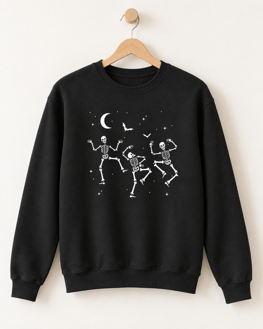 Black adult Halloween sweatshirt with three dancing skeletons, bats and crescent moon displayed on a wooden hanger.