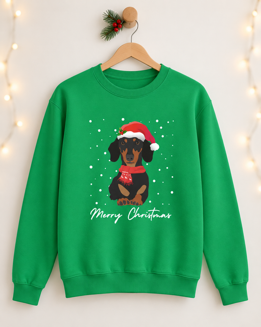 A unisex adults bright green crewneck sweatshirt hanging on a wooden hanger against a warm white wall with soft string lights. The sweatshirt features a graphic of a black and tan dachshund wearing a red Santa hat and scarf, with white snowflakes and the text 'Merry Christmas' below.