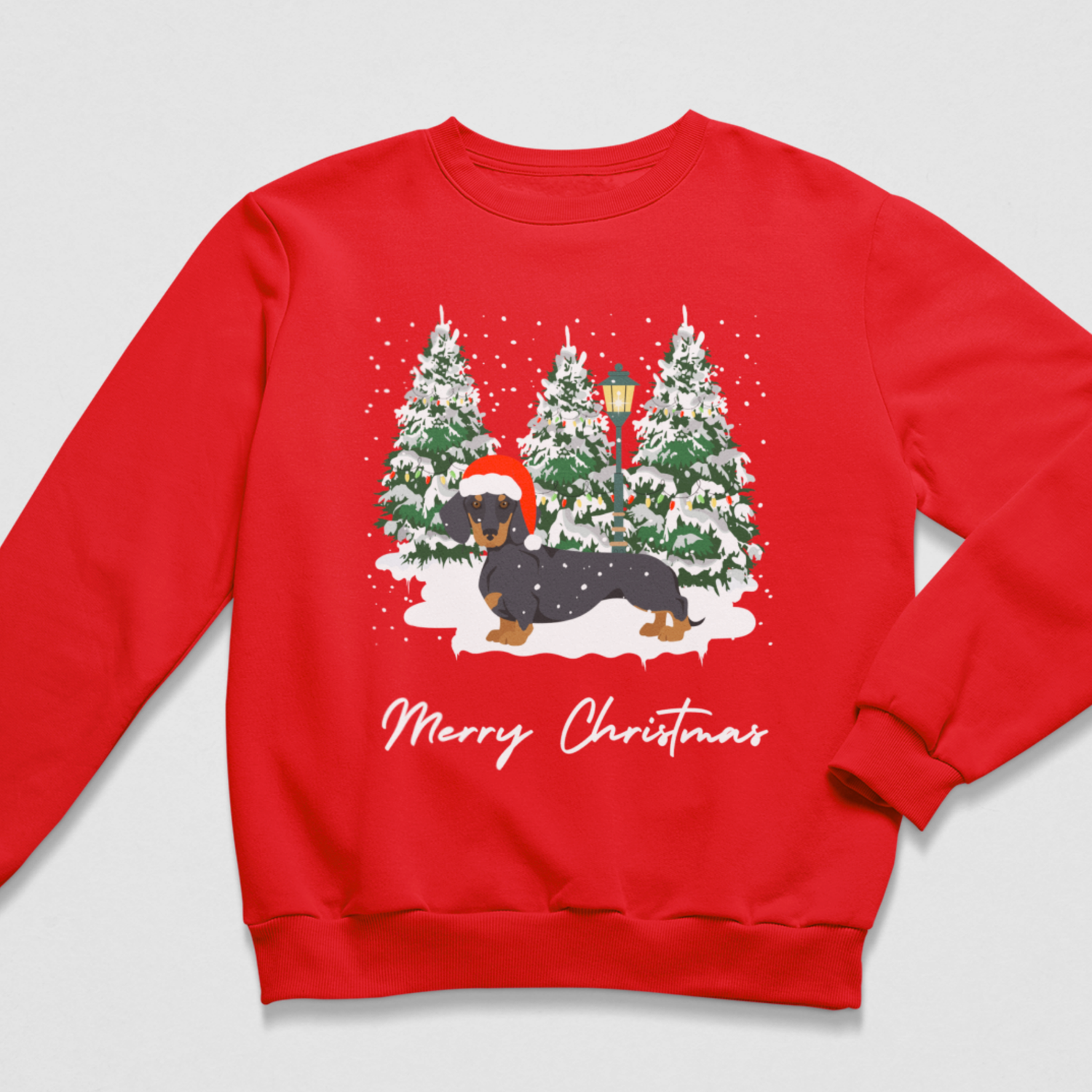 A red crewneck sweatshirt featuring a festive Christmas graphic of a dachshund in a snowy winter scene with pine trees and the text 'Merry Christmas' printed below.