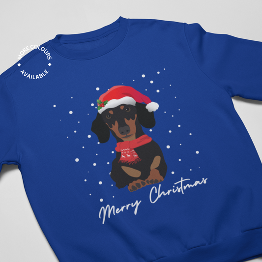 A blue Christmas sweatshirt featuring an illustration of a Dachshund wearing a Santa hat and a red winter scarf, with 'Merry Christmas' text at the bottom.