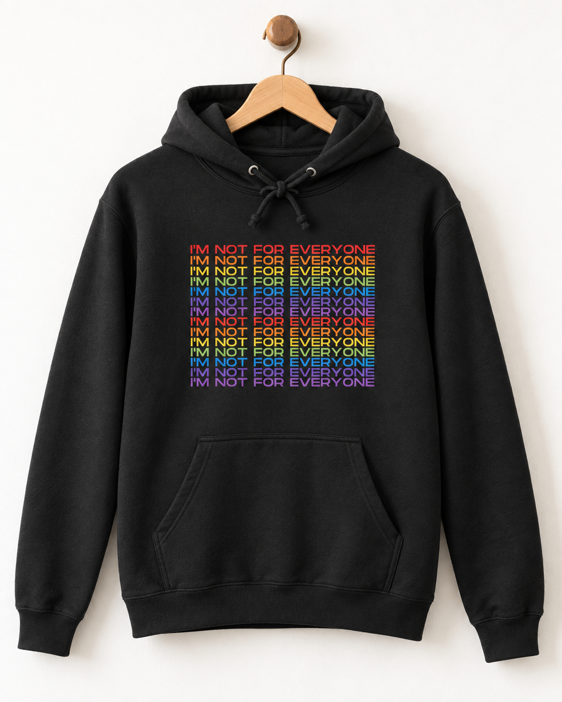 Black adult hoodie on a wooden hanger featuring a stacked rainbow “I’m Not For Everyone” slogan print.