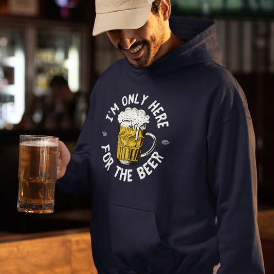 Man in a pub wearing navy “I’m Only Here for the Beer” hoodie while holding a pint of beer