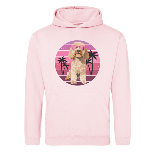 A light pink unisex adult hoodie with a graphic of a cockapoo dog wearing sunglasses, surrounded by a pink circle and palm trees in the background.